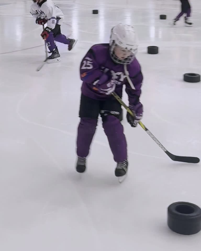 A Galaxy player in purple skates toward the camera with a stick on the ice