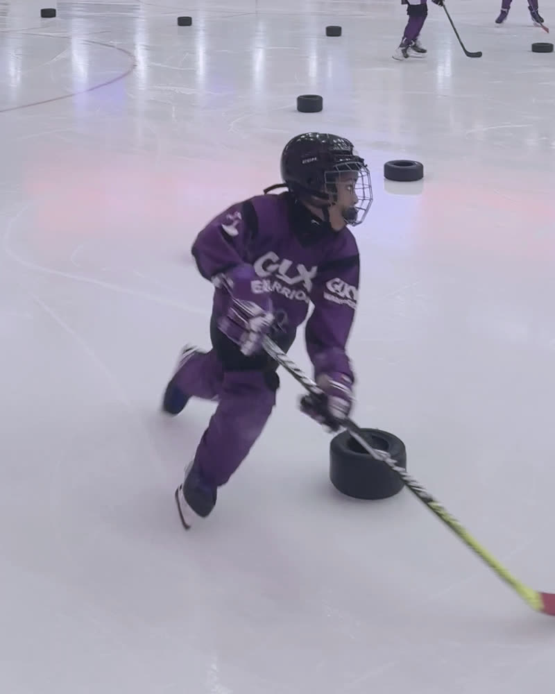A Galaxy player in purple controls a puck on the ice